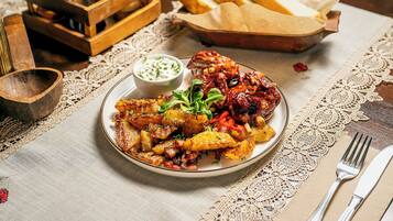 A plate of food with a side of sauce and bread on a table with a lace tablecloth.