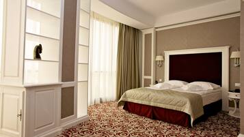 A hotel room with a large bed, a wardrobe, a vanity with a mirror, and a patterned carpet.