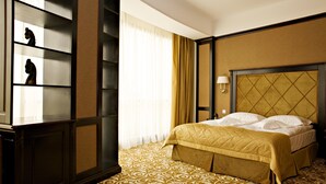 Habitación de hotel con una cama grande, una mesita de noche, una lámpara y una estantería con adornos.