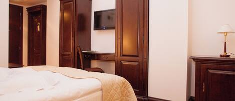 A hotel room with a bed, a desk, a television, and a lamp.