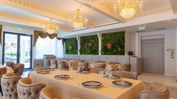 A formal dining room with a long table set for a meal, elegant chairs, and a chandelier. - W Regal Boutique&Spa (Constanta)