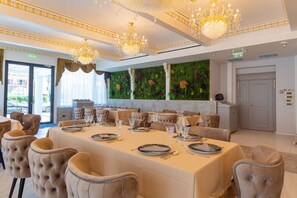 A formal dining room with a long table set for a meal, elegant chairs, and a chandelier. - W Regal Boutique&Spa (Constanta)
