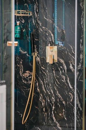 A bathroom with a black marble wall, a gold showerhead, and a glass shower enclosure. - W Regal Boutique&Spa (Constanta)