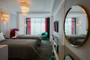 A hotel room with two beds, a green armchair, a TV, and a large mirror. - W Regal Boutique&Spa (Constanta)
