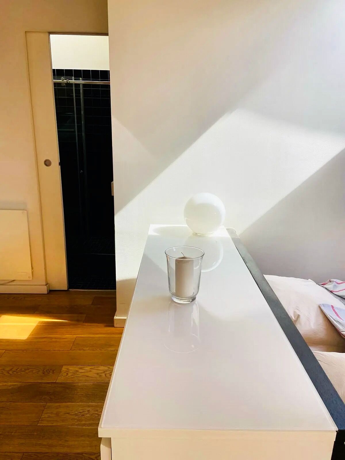 A room with a white table, a glass of water, and a white spherical object.