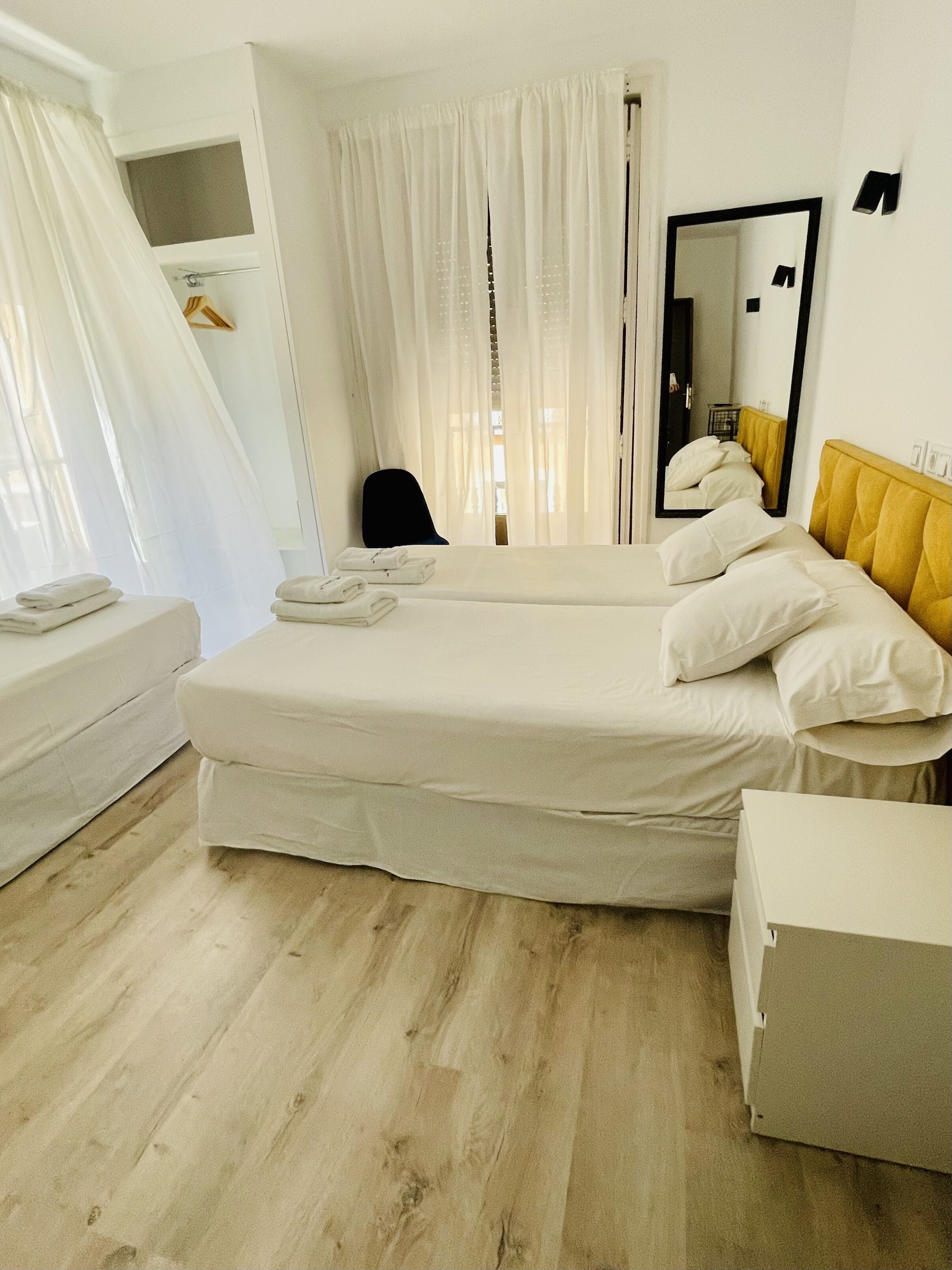 Una habitación de hotel con una cama, una silla, un espejo y un armario.