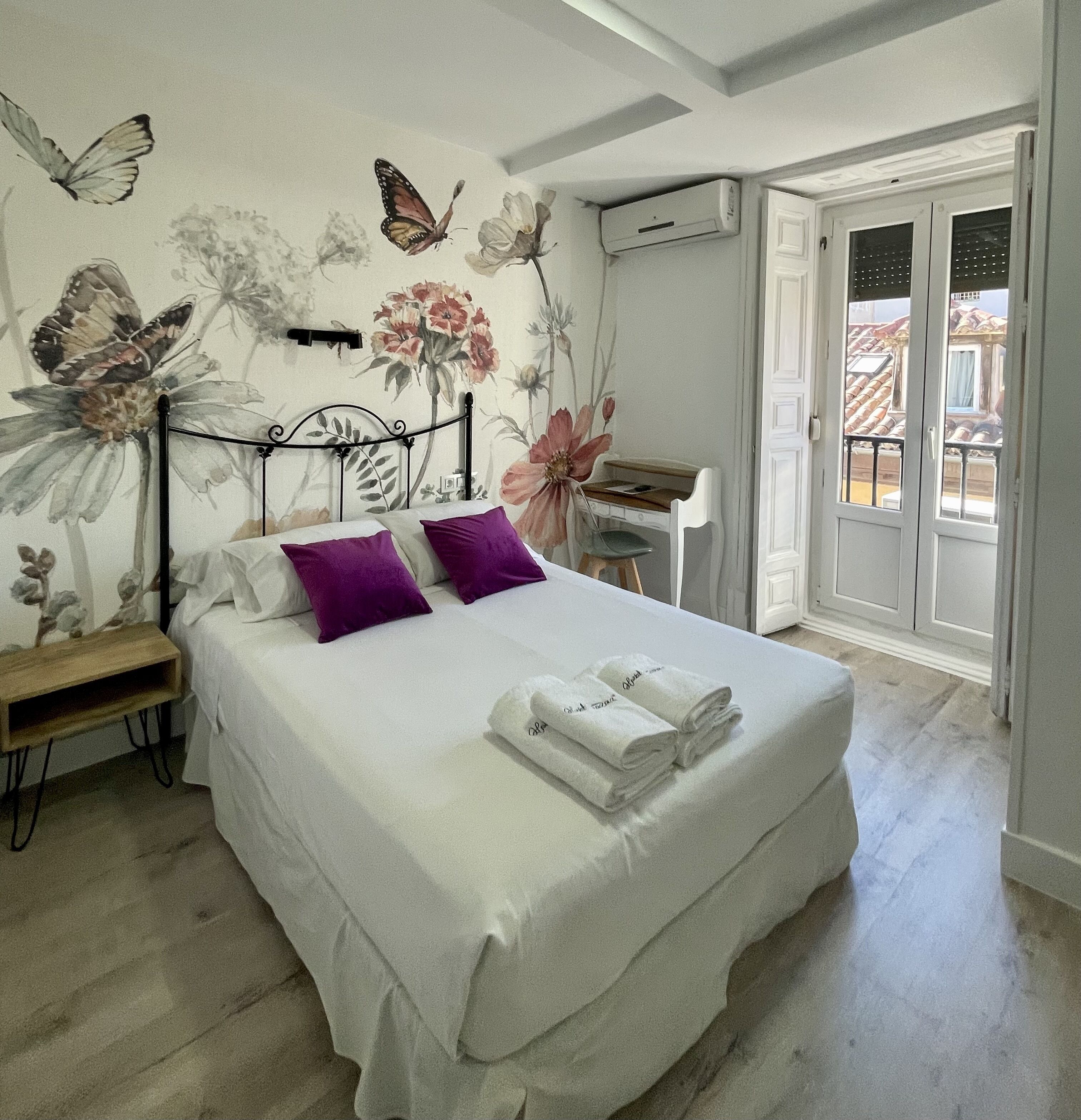 A bedroom with a bed, pillows, a desk, and a window.