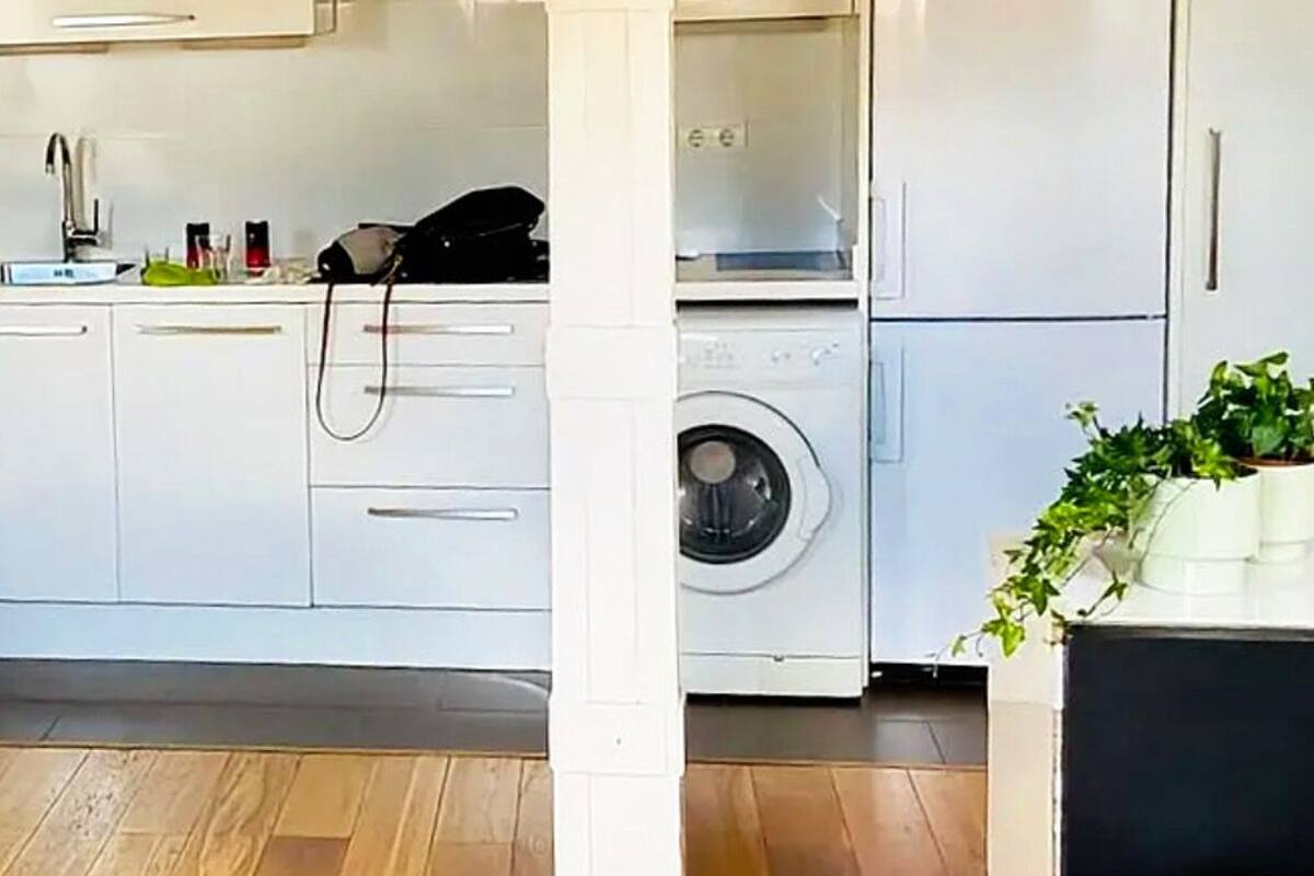 A compact kitchen with white cabinets, a washing machine, and a ceiling fan.