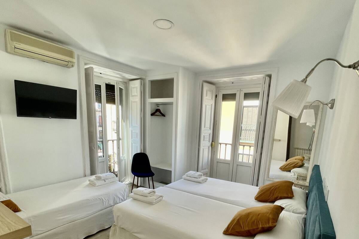 A hotel room with two beds, a desk, a chair, a TV, and a mirror.