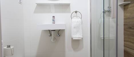 Un baño moderno con inodoro, lavamanos, espejo y ducha.