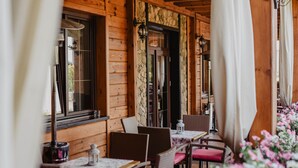A wooden cabin-style restaurant with tables and chairs, a stone wall, and a flower arrangement. - Hotel Czardasz Spa & Wellness (Plock)