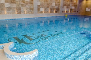 A swimming pool with a tiled floor and a wall with mosaic tiles. - Hotel Czardasz Spa & Wellness (Plock)