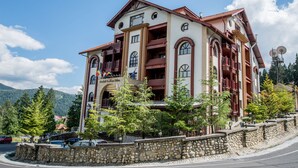 A multi-story hotel with balconies, a stone facade, and a mountainous backdrop. - Predeal Comfort Suites (Predeal)