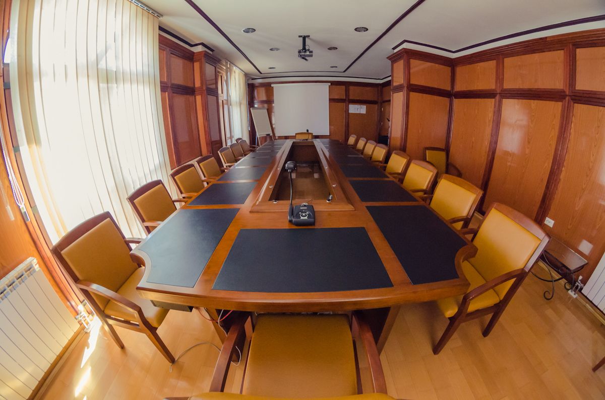 A conference room with a long table, chairs, a projector, and a whiteboard.
