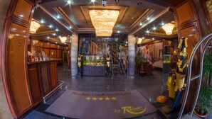 A hotel lobby with a grand chandelier, a reception desk, and a staircase leading to upper floors. - Predeal Comfort Suites (Predeal)