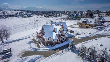 A snow-covered village with traditional houses, a ski lift, and a river.