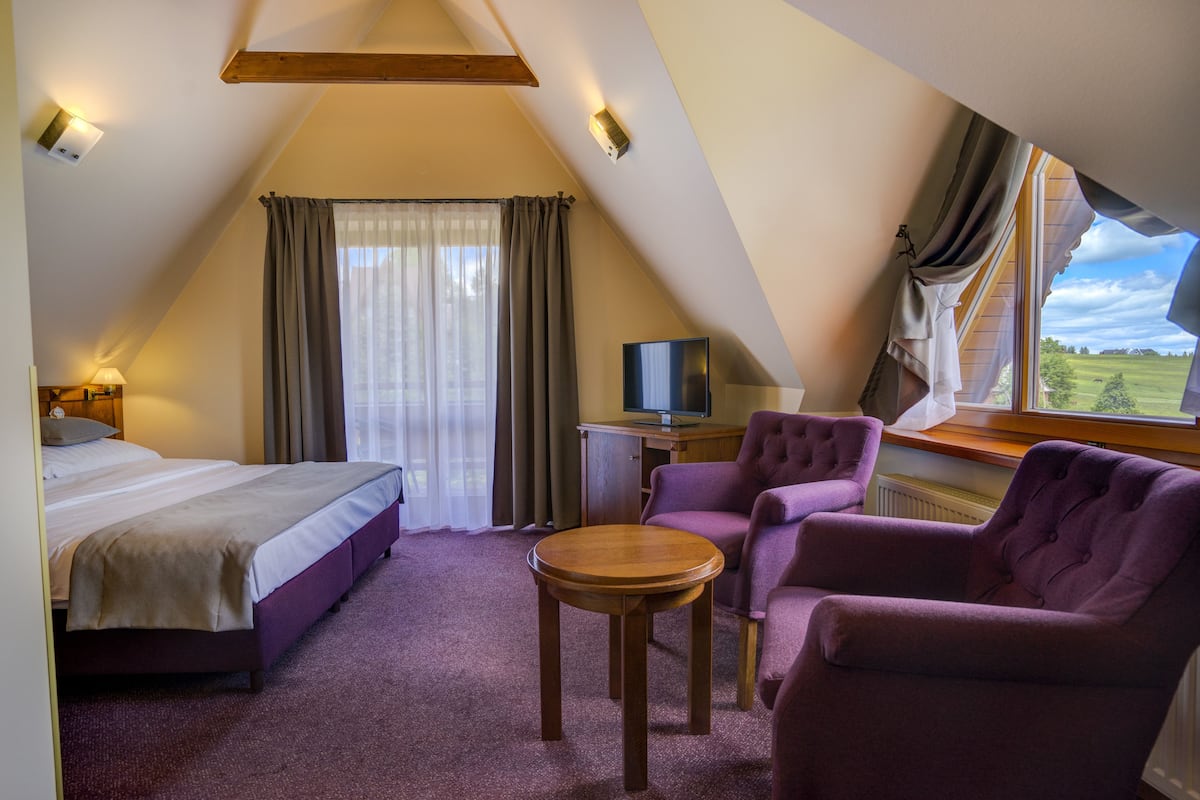 A room with a bed, a desk with a computer, a chair, and a table.