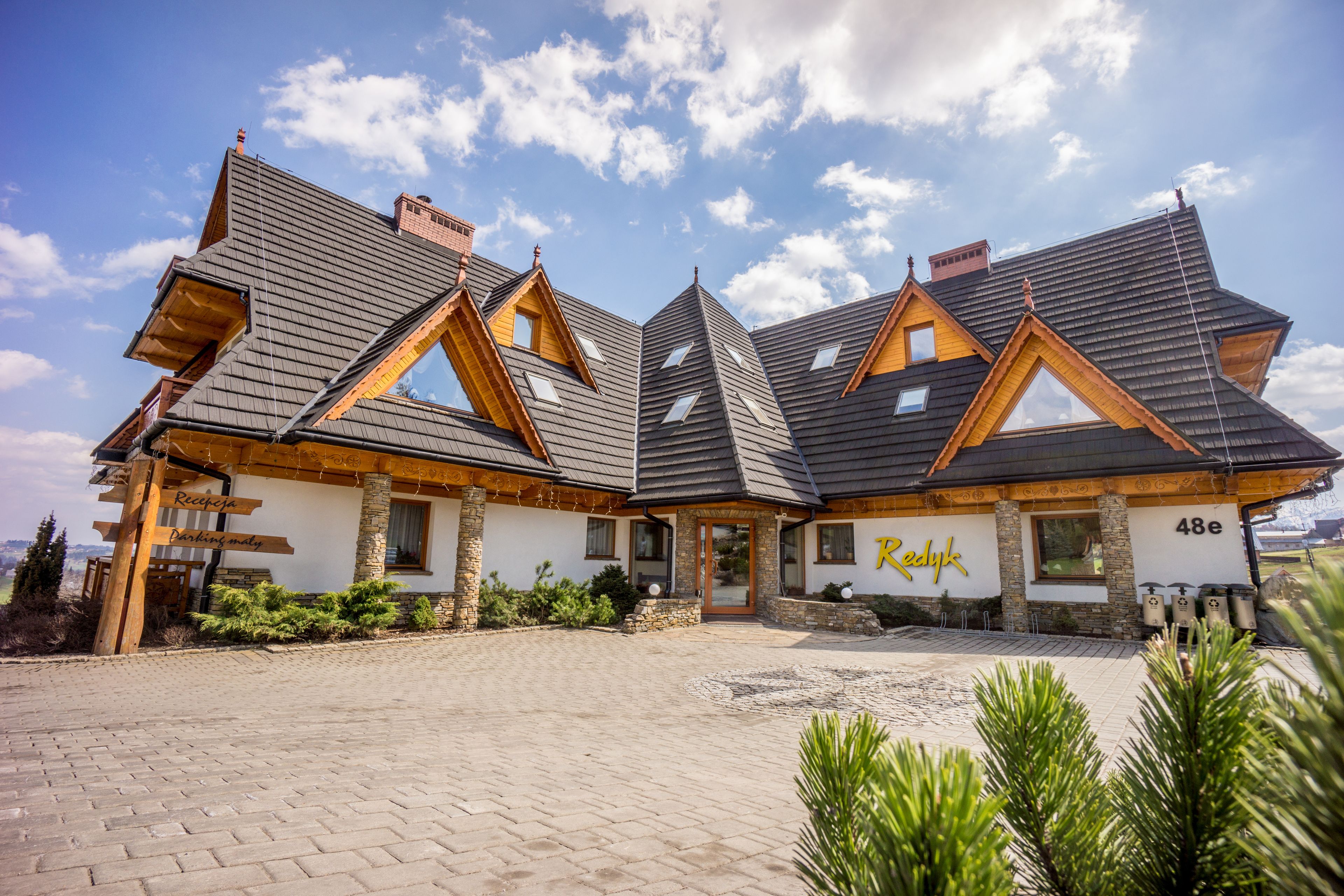 A modern building with a sloped roof, stone pillars, and a sign reading "Redyk."