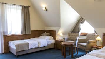 A hotel room with a bed, two armchairs, a small table, and a nightstand with a lamp.