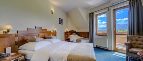 Une chambre d’hôtel avec deux lits, une tête de lit en bois, des lampes de chevet, une chaise et une vue sur les montagnes par la fenêtre.