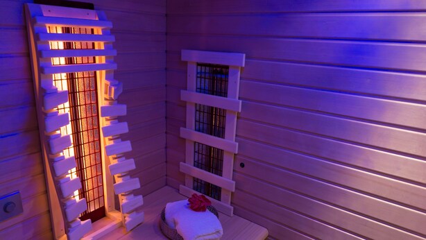 A sauna with wooden walls and benches, featuring a central heated bench and a window with bars. - Königsteiner Hof (Königstein)