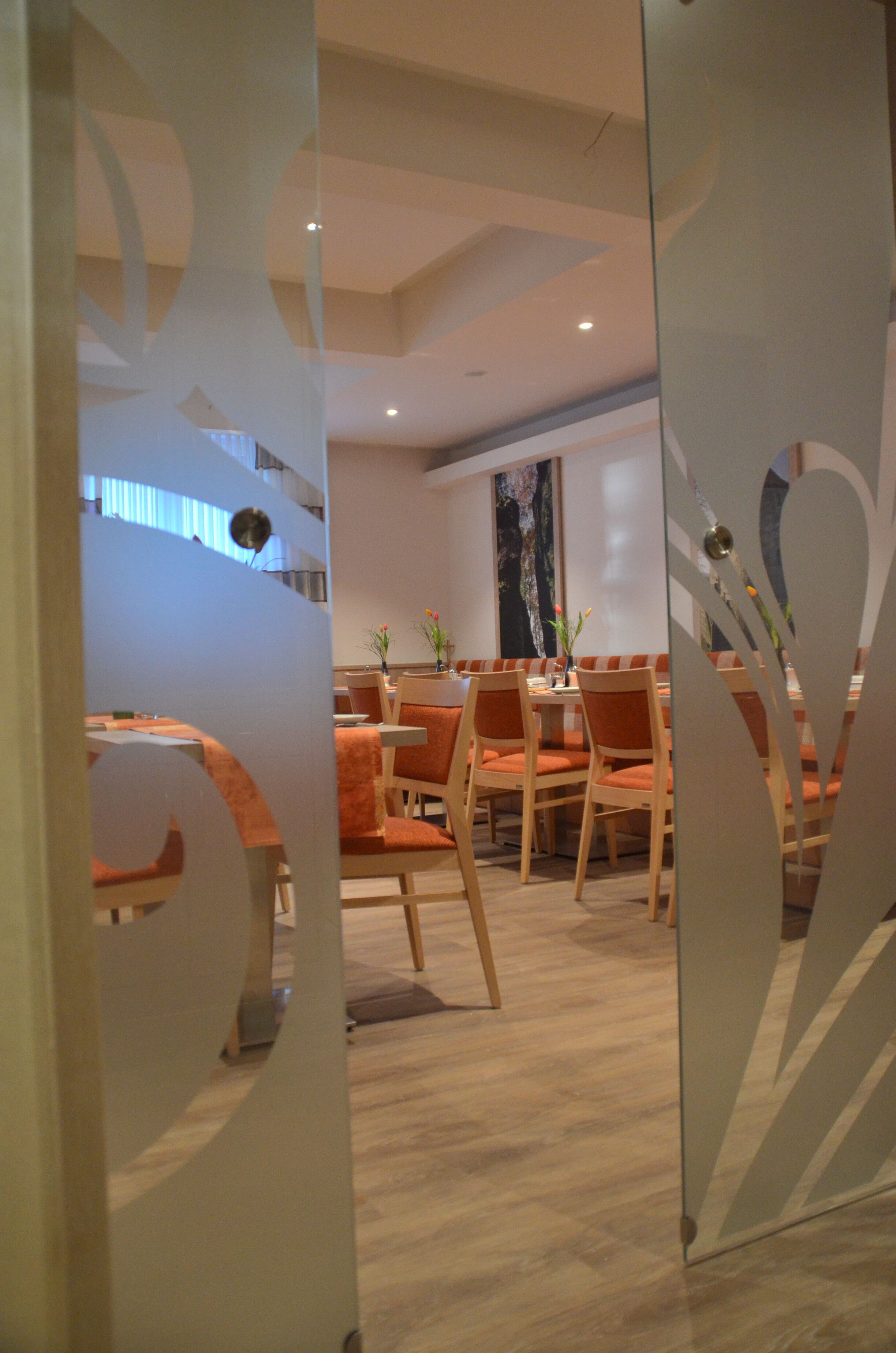 A modern dining area with wooden furniture and glass partitions.