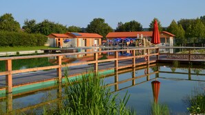 A lakeside hotel with a wooden deck, outdoor seating, and a red umbrella. - Königsteiner Hof (Königstein)