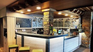 A bar area with a wooden counter, bar stools, and a stone pillar. - Königsteiner Hof (Königstein)