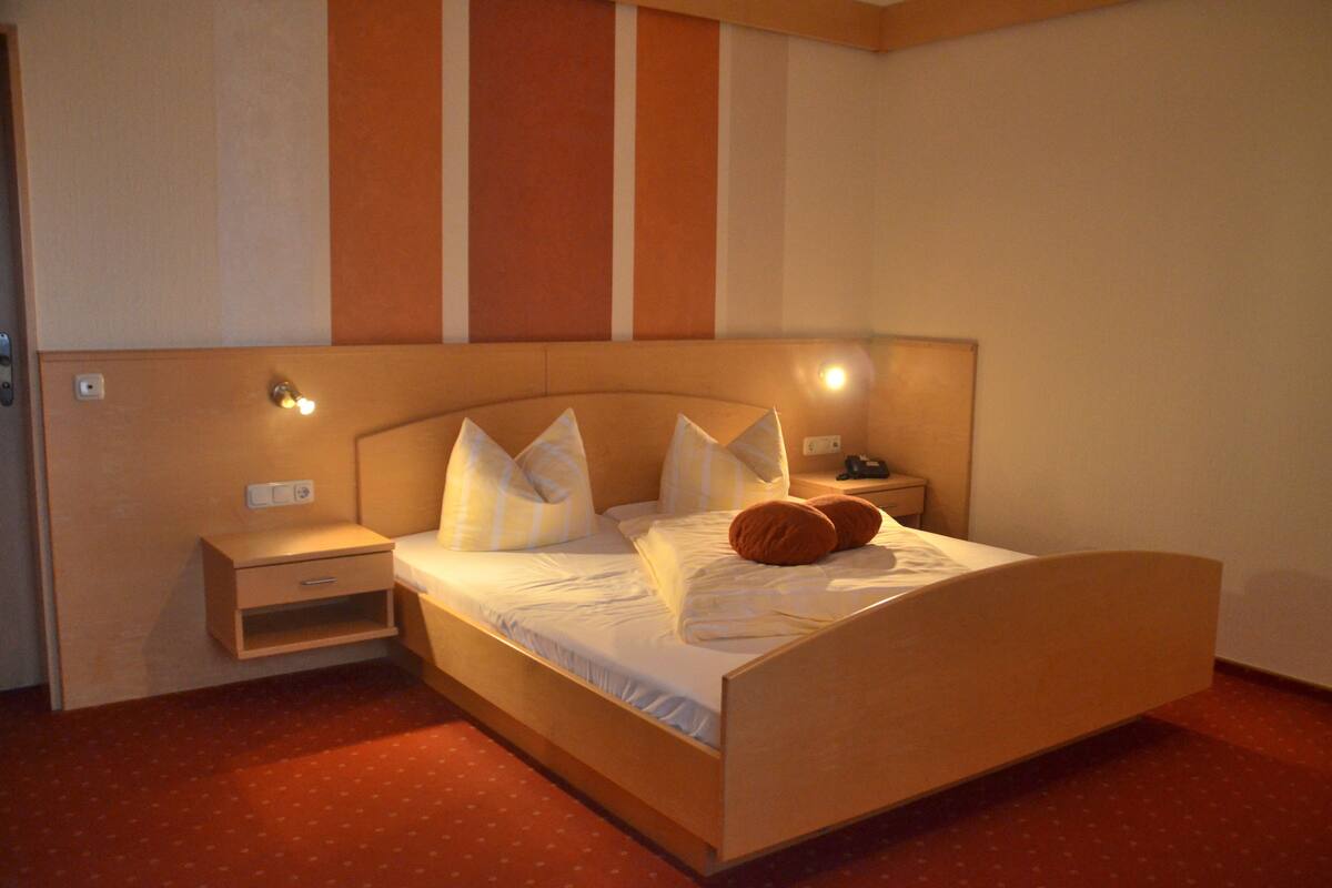 A neatly made bed with pillows and a bedside table in a hotel room.