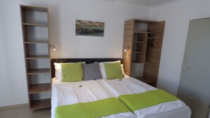 A neatly made bed with green and white bedding, a headboard with built-in shelves, and a small landscape painting on the wall. - Art Inn Hotel Dinslaken (Dinslaken)
