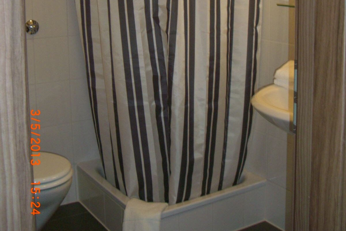 A bathroom with a shower curtain, toilet, and sink.