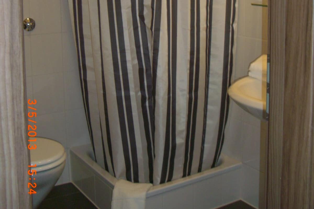 Een badkamer met douchegordijn, toilet en wastafel.