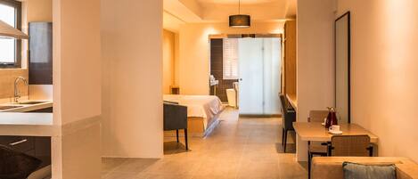 A modern hotel room with a kitchenette, a dining area, and a separate bedroom.