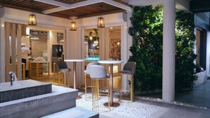 An outdoor seating area with a bar, a water feature, and a lush green wall.