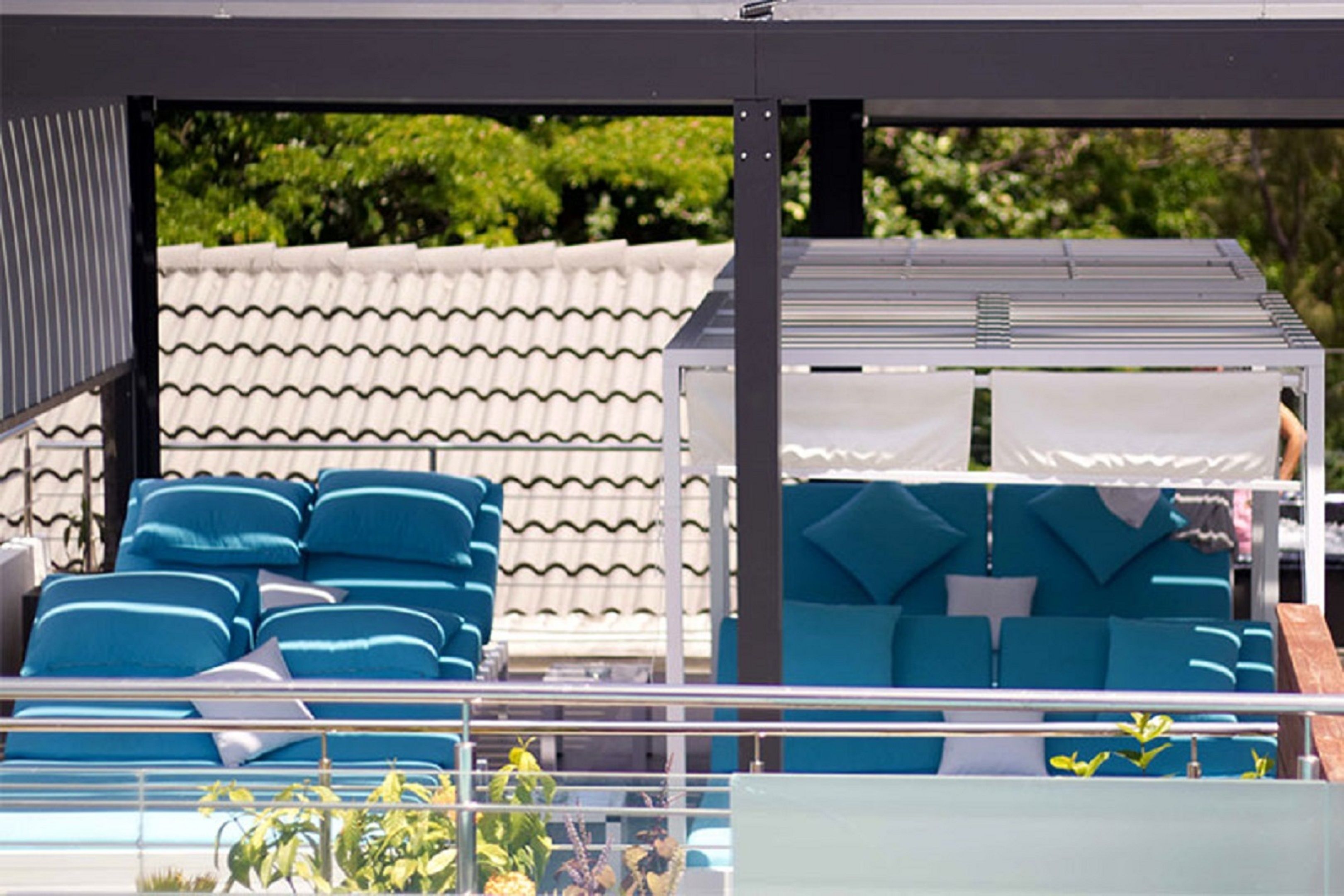 A covered outdoor seating area with blue cushioned sofas and a white awning.