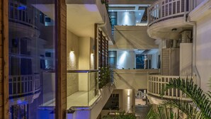 A multi-level atrium with glass railings, indoor plants, and a central staircase.