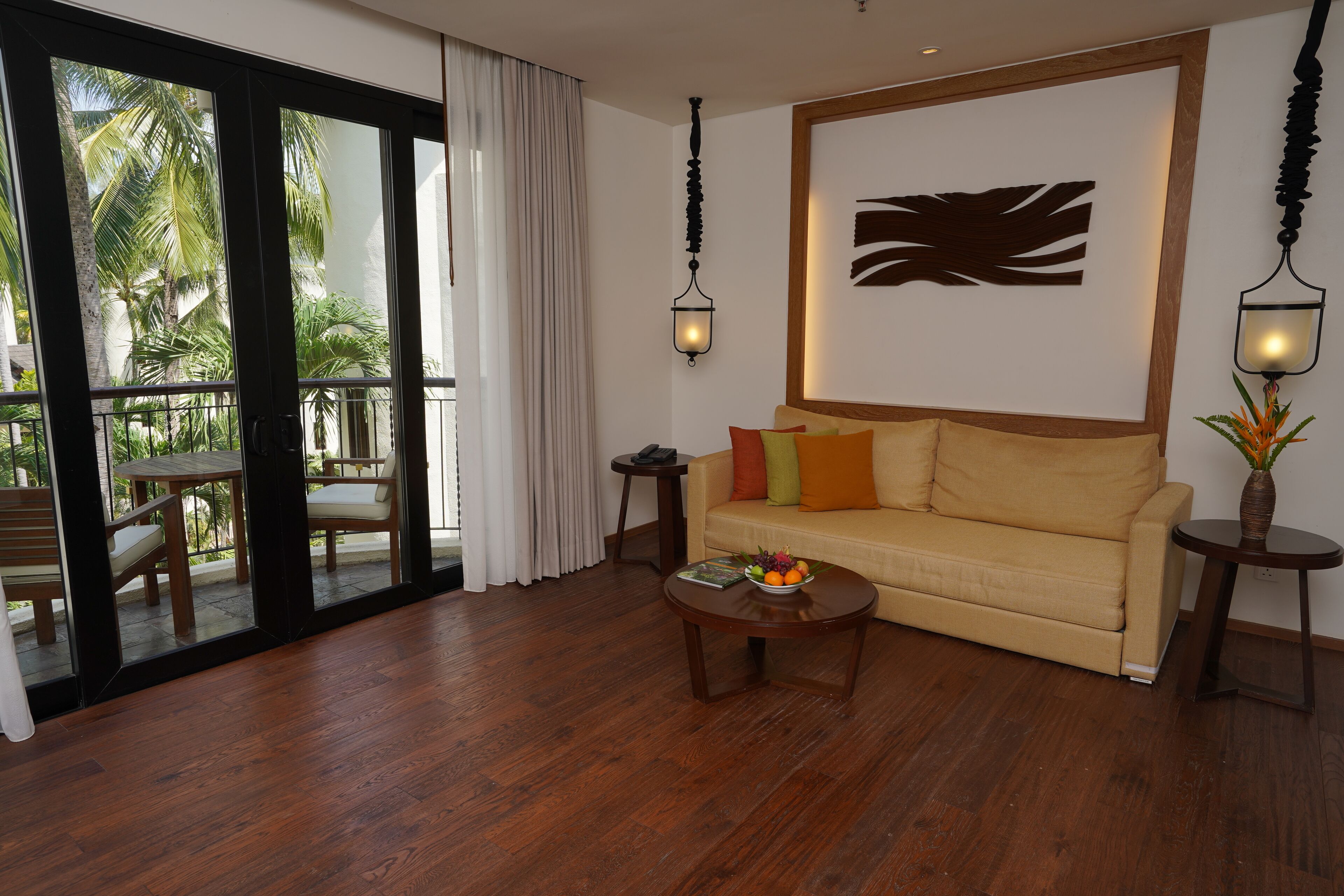 A living room with a sofa, coffee table, and a view of a balcony with outdoor furniture.