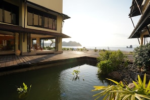 A modern building with a pool, wooden deck, and a view of the sea.
