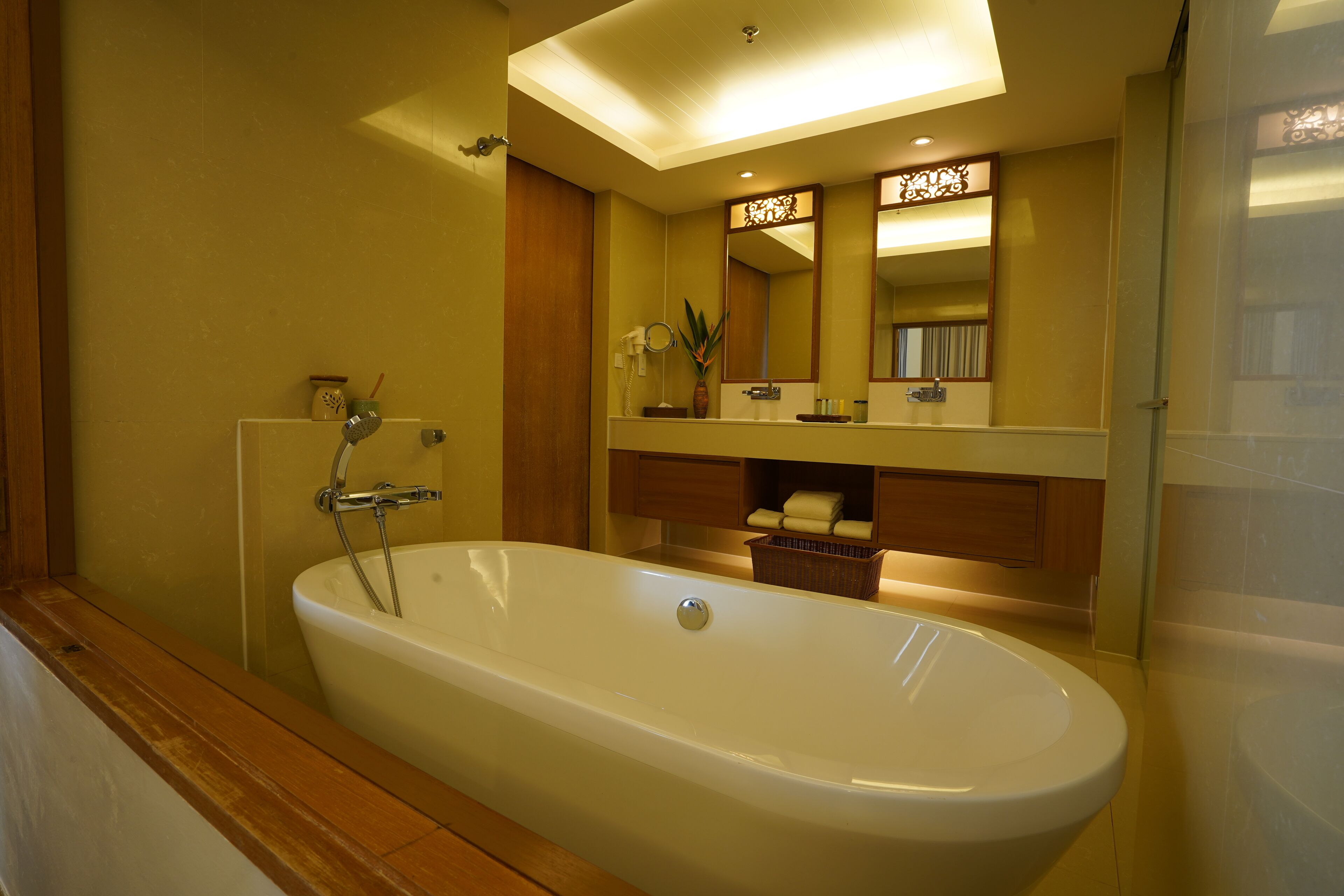 Un baño moderno con una bañera independiente, tocador de madera y un espejo grande.