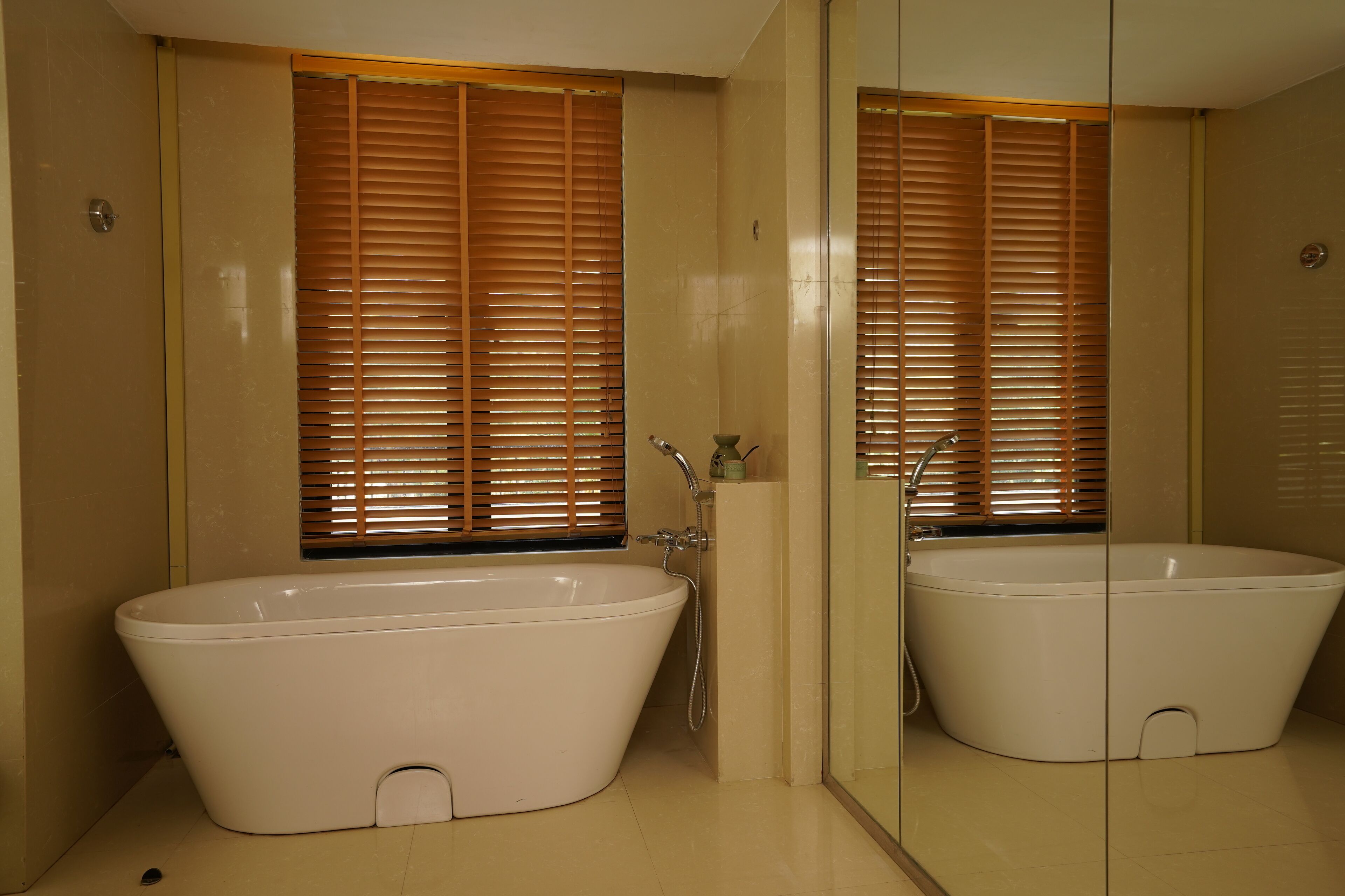 Un baño con una bañera independiente, un espejo y persianas de madera.