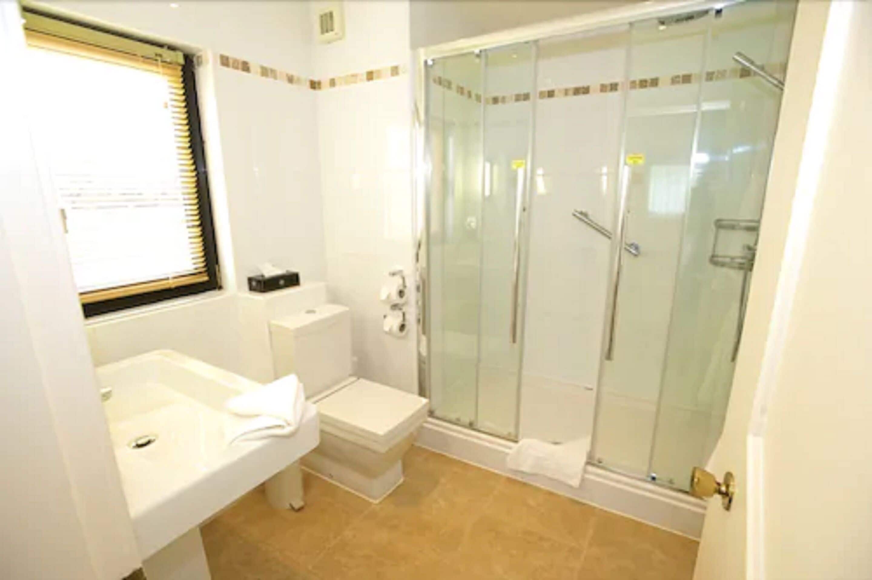 A bathroom with a toilet, sink, and glass-enclosed shower.