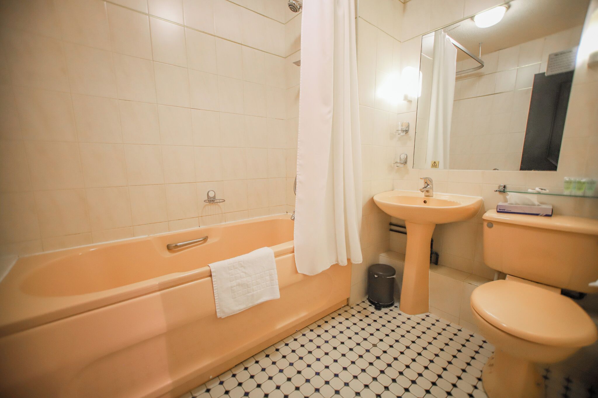 A bathroom with a bathtub, sink, toilet, and a mirror.