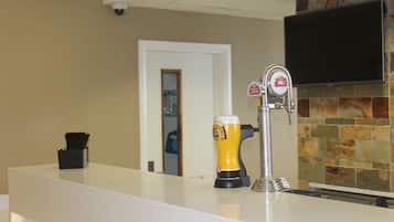 A bar area with a tap, a beer mug, and a TV mounted on the wall.