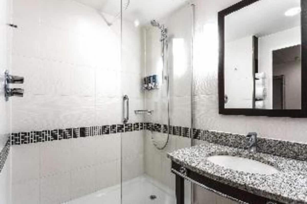 Un baño con ducha, lavamanos y espejo.