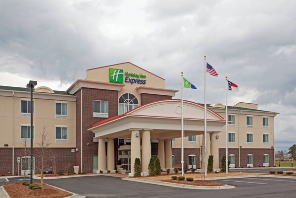 A Holiday Inn Express building with a brick facade, a covered entrance, and multiple flags.