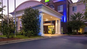 Een Holiday Inn Express hotel met een modern design, met een opvallende ingang en een aangelegde tuin ervoor.