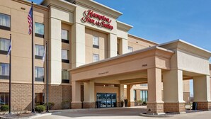 A Hampton Inn & Suites building with a clear entrance, American flags, and a sign indicating a 12'6" clearance. - Hampton Inn & Suites Peoria at Grand Prairie, IL (Peoria)