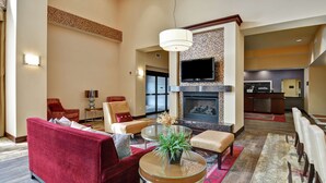 A spacious living area with a fireplace, comfortable seating, and a television. - Hampton Inn & Suites Peoria at Grand Prairie, IL (Peoria)