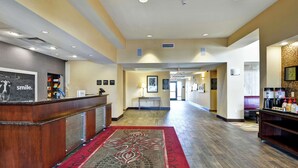 A hotel lobby with a reception desk, a red carpet, and a hallway leading to other areas. - Hampton Inn & Suites Peoria at Grand Prairie, IL (Peoria)
