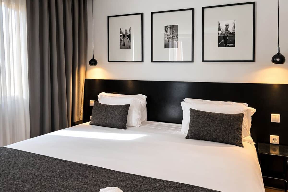 A hotel room with a large bed, dark headboard, and three framed pictures on the wall.